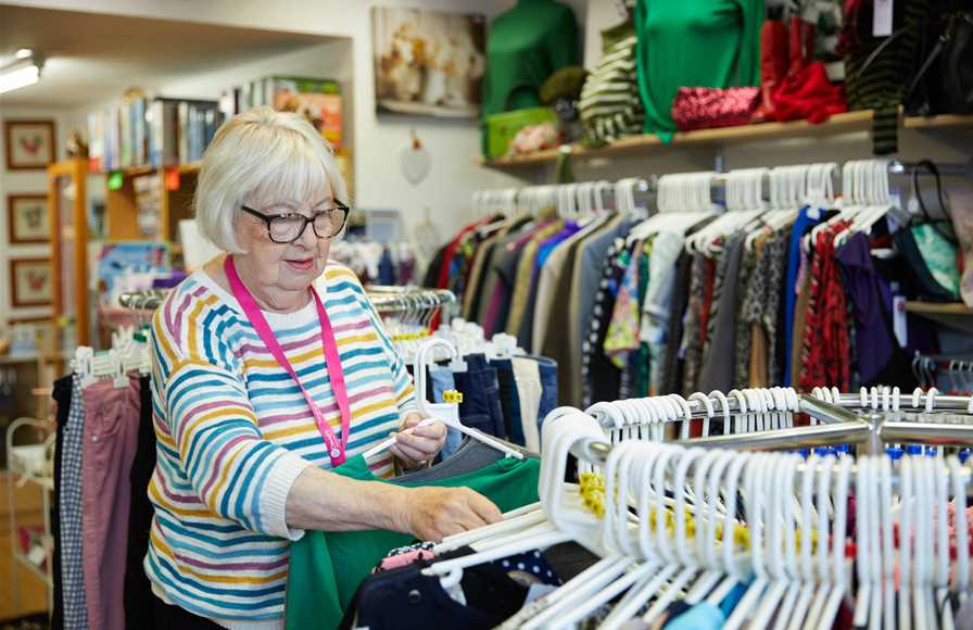 One of our shop workers putting clothes on a rack.